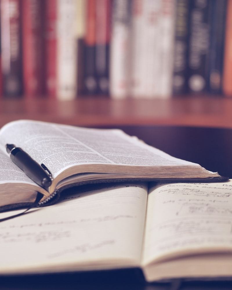 An open book on a desk in front of a bookshelf